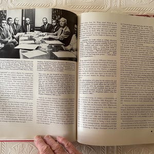 Puede incluir: Un libro abierto con fotograf&iacute;as y texto en blanco y negro. Una foto muestra a un grupo de hombres sentados alrededor de una mesa. El texto de la p&aacute;gina trata sobre la NAACP y Martin Luther King Jr. El libro est&aacute; abierto en las p&aacute;ginas 52 y 53.