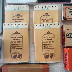 May include: A collection of vintage office supplies, including several beige Visible Record Forms notebooks with the text "Town Bond" and "50 Visible Record Forms". Also, there are boxes of gummed labels and index cards.