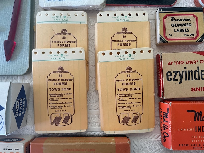 May include: A collection of vintage office supplies, including several beige Visible Record Forms notebooks with the text "Town Bond" and "50 Visible Record Forms". Also, there are boxes of gummed labels and index cards.