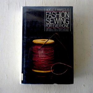 May include: A book titled "Fashion Sewing for Everyone" by Adele P. Margolis. The cover features a spool of red thread with a needle and a dark background.