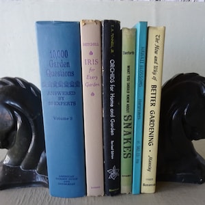 May include: A set of black horse bookends holding a collection of vintage gardening books with titles like "10,000 Garden Questions", "Iris for Every Garden", "Orchids for Home and Garden", "What You Should Know About Snakes", "Hawaii Blossoms", and "The How and Why of Better Gardening".