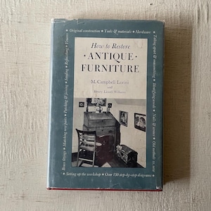 May include: A book titled "How to Restore *ANTIQUE* FURNITURE" by M. Campbell Lorini and Henry Lionel Williams. The book cover features a photo of a vintage writing desk and chair in a room with a window. The book cover also lists over 150 step-by-step diagrams.