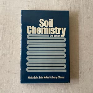 May include: A blue hardcover book titled "Soil Chemistry" with the subtitle "2nd Edition". The book has a white stripe design on the cover and the authors' names are listed below the title: Hinrich Bohn, Brian McNeal & George O'Connor.