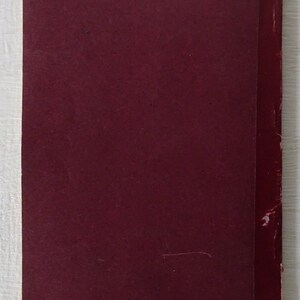 Peut inclure: Un livre de couleur bordeaux avec une reliure rouge. Le livre est ferm&eacute; et a une couverture textur&eacute;e.