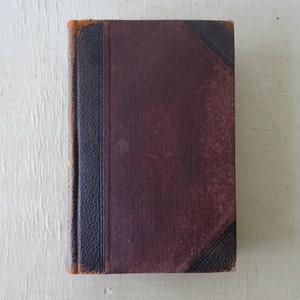 May include: A vintage brown leather-bound book with black accents and a textured cover.