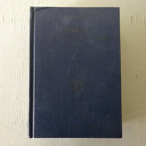 May include: A dark blue hardcover book with a title and author's name on the front cover. The book is slightly worn and has a textured cover.