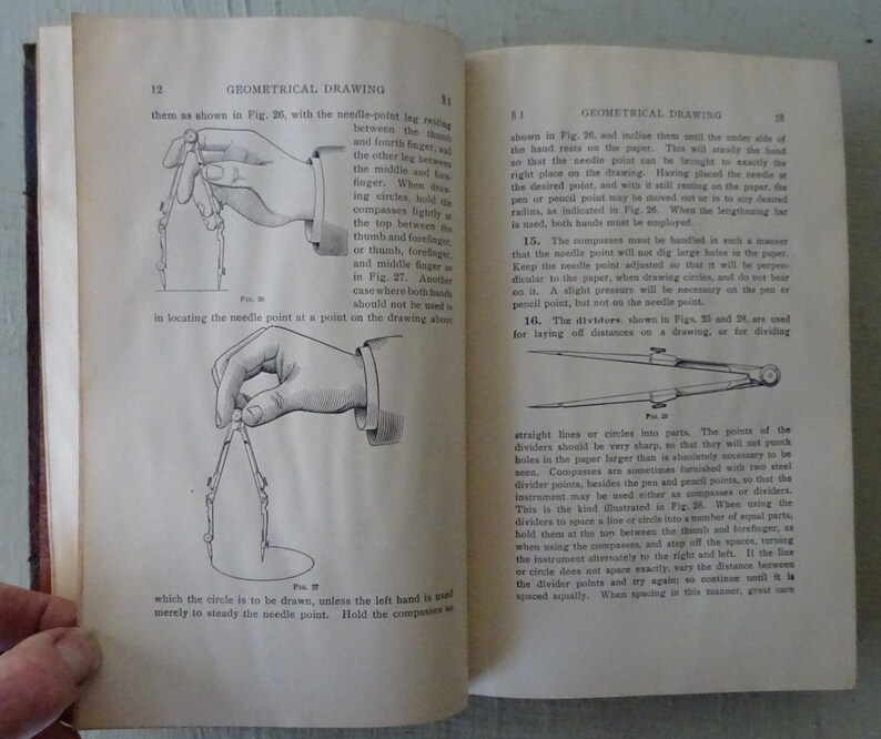 May include: A black and white illustration of a hand holding a pair of compasses. The compasses are used for drawing circles. The illustration shows the correct way to hold the compasses to draw a circle.