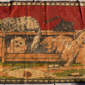 May include: A vintage tapestry rug with a red background featuring a scene of cats in a cage. The cats are brown, white, and black. The rug has a fringe border and is woven with intricate details.