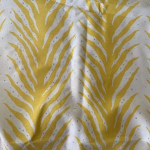 May include: White fabric with a repeating pattern of yellow, leaf-like shapes. The yellow shapes have a textured appearance and are accented with small, gray dots. The design is reminiscent of a tropical or botanical theme.