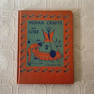 May include: Vintage hardcover book titled "Indian Crafts and Lore" with an orange cover and a green and orange illustration. The illustration depicts a Native American figure, a teepee, and the text "A Big Golden Book".