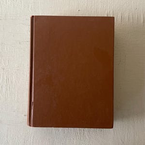 May include: A brown hardcover book with a plain cover.