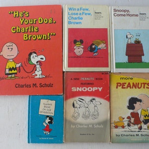 May include: A collection of vintage Peanuts books by Charles M. Schulz. The books feature Snoopy, Charlie Brown, and other characters. Titles include "He's Your Dog, Charlie Brown!" and "Snoopy, Come Home."