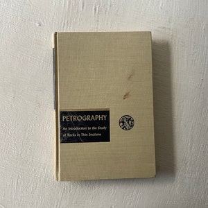 May include: A beige book with the title "Petrography: An Introduction to the Study of Rocks in Thin Sections" printed on the cover.