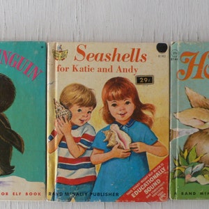 May include: Three vintage children's books with colorful covers. Titles include "Little Penguin," "Seashells for Katie and Andy," and "Hoppity." The books feature illustrations of a penguin, children with seashells, and a rabbit with a butterfly.