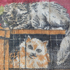 May include: A vintage tapestry featuring two cats, one with a green leafy branch behind it, and the other in a cage. The tapestry has a brown, orange, and red color scheme.