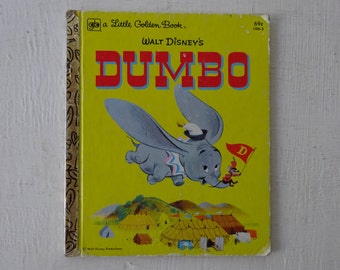 May include: A vintage Little Golden Book featuring Walt Disney's Dumbo. The cover shows Dumbo flying with his large ears, a mouse holding a flag with a 'D' on it, and a circus tent scene in the background.