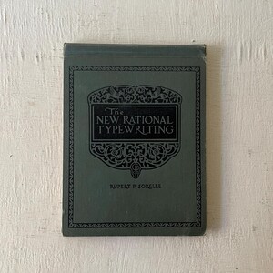 May include: The cover of a dark green book titled "The New Rational Typewriting" by Rupert P. Sorelle. The title is in a decorative font with a black and white design.