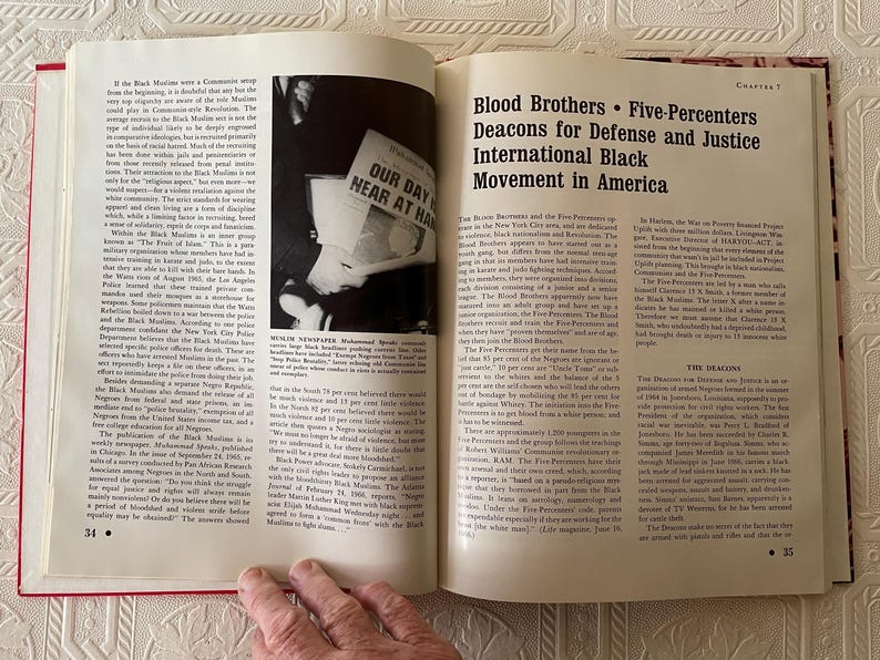 Puede incluir: Un libro abierto con tapas rojas, que muestra texto y una fotograf&iacute;a en blanco y negro. El texto incluye el t&iacute;tulo "Blood Brothers &bull; Five-Percenters Deacons for Defense and Justice International Black Movement in America."