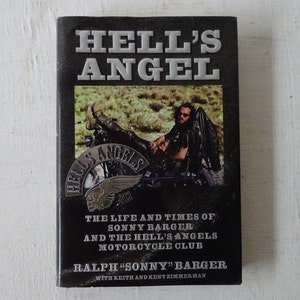 May include: A black and white book titled "Hell's Angel: The Life and Times of Sonny Barger and the Hell's Angels Motorcycle Club" by Ralph "Sonny" Barger with Keith and Kent Zimmerman. The cover features a black and white photo of a man sitting on a motorcycle.