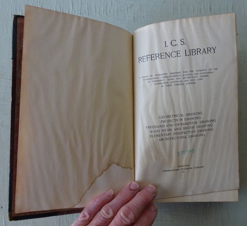May include: A vintage book titled "I.C.S. Reference Library" with a list of drawing courses: Geometrical Drawing, Projection Drawing, Freehand and Ornamental Drawing, Wash Work and Brush Drawing, Elementary Perspective Drawing, and Architectural Drawing. The book has a number "378986" printed on the bottom right corner.