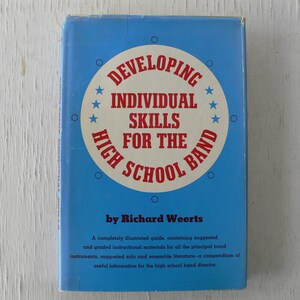 May include: A vintage book titled "Developing Individual Skills for the High School Band" by Richard Weerts. The cover is light blue with a circular design in red and white, featuring text and stars. The book's title is prominently displayed.