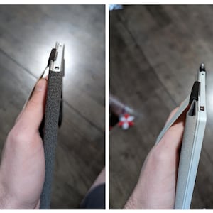 May include: A grey and black tablet case with a hand strap. The case is made of a textured fabric and has a black strap. The tablet is white and has a black strap.