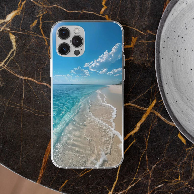 May include: Transparent phone case displaying a beach scene. The image shows a blue sky with white clouds, a turquoise sea, and a sandy shore. The case has a clear edge and a camera aperture.
