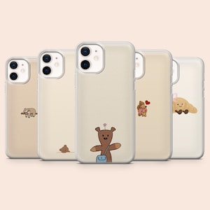 May include: Five beige phone cases featuring cartoon bear illustrations. Each case has a clear protective cover. The bears are depicted in different scenarios, such as a bear with a backpack, a bear couple, and a sleeping bear.