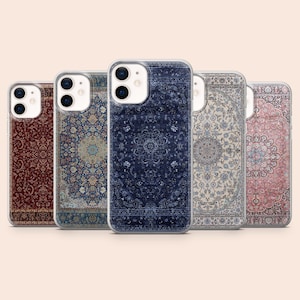 May include: Five phone cases with intricate rug designs in various colors, including deep red, navy blue, and cream. Each case features a clear border, showcasing the phone's design. The rug patterns are detailed and symmetrical.