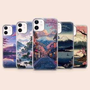 以下が含まれることがあります： 日本の風景デザインの携帯電話ケース5つ。各ケースには、山、桜、伝統的な建物など、さまざまな風景が描かれています。ケースは透明な縁取りと光沢のある仕上がりです。