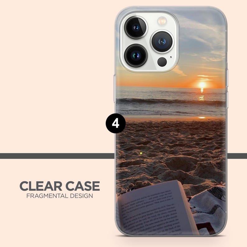May include: Clear phone case featuring a beach sunset scene. The case shows a sunset over the sea, with a book and towel on the sand. The text "CLEAR CASE FRAGMENTAL DESIGN" is printed on the case.