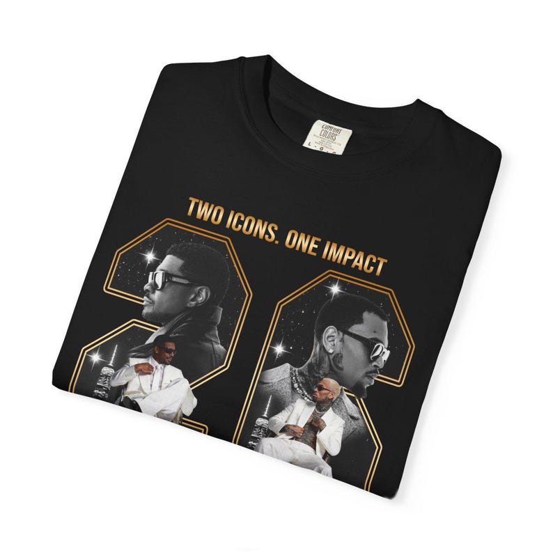 May include: A black t-shirt featuring a graphic print with the text "TWO ICONS. ONE IMPACT" in gold lettering. The design includes two large gold-outlined numbers and photographic portraits of two individuals wearing sunglasses and white suits.