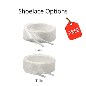 May include: White satin and tulle shoelaces are displayed. The text "Shoelace Options" is at the top. A red tag with the word "FREE" is in the upper right corner. The satin shoelaces are above the tulle shoelaces.