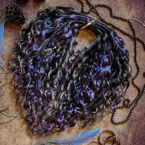May include: A bundle of curly, dark dreadlocks with streaks of purple and blue. The dreadlocks are tied together with a ribbon. Decorative beads and blue accents are woven throughout the hair. The image is styled with feathers and jewelry.