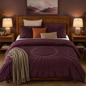Peut inclure: Une chambre à coucher avec un lit doté d'une couette violet foncé et de coussins assortis. La couette présente un motif circulaire au centre. Une couverture de couleur neutre est drapée sur le lit. La pièce est décorée de meubles en bois et d'un tapis de couleur neutre.