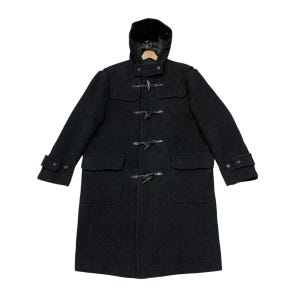 Pode incluir: Um casaco duffle coat preto de lã com capuz e fechos de alternância. O casaco tem dois bolsos frontais e punhos abotoados. Este casaco clássico é adequado para o clima frio. O casaco tem aproximadamente 122 cm de comprimento.
