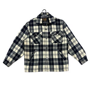 May include: A black and cream checked jacket with a button-down front, two chest pockets, and side pockets. The jacket is hanging on a black hanger. The label reads "BIG JOHN".