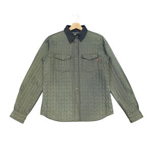 Puede incluir: Chaqueta camisa acolchada verde oliva con cuello de mezclilla oscuro y dos bolsillos en el pecho. La chaqueta tiene cierre de botones y mangas largas. Una pequeña etiqueta roja es visible en el bolsillo derecho.
