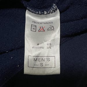 Puede incluir: Primer plano de una etiqueta de ropa blanca con texto y s&iacute;mbolos negros. La etiqueta incluye el texto "MEN'S - S" e instrucciones de lavado. La composici&oacute;n del tejido es 80% algod&oacute;n y 20% poli&eacute;ster.