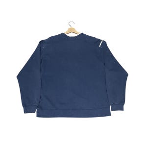 Puede incluir: Una taza de cer&aacute;mica blanca con asa negra y el texto "But First, Coffee" en negro y negrita. La taza est&aacute; sobre una superficie de madera.