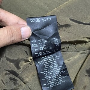 May include: A black clothing tag with Japanese text and care instructions. The tag lists fabric composition: wool, nylon, and acrylic. Washing and drying instructions are also included.