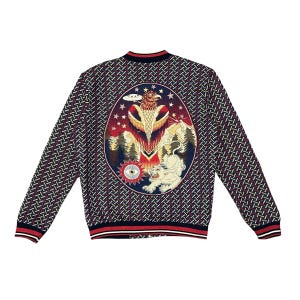 Könnte beinhalten: Eine langärmelige Bomberjacke mit dunkelblauem und weißem geometrischem Muster. Die Rückseite zeigt eine große ovale Grafik mit einem Adler, einem weißen Tiger, Wald, Bergen, Sternen, einer fliegenden Untertasse und einem Auge, mit rot-weißem Saum.