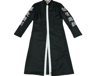May include: Black long coat with white trim and Japanese text on the sleeves. The coat features a stand-up collar and a full-length design. The coat is hanging on a hanger against a white backdrop.