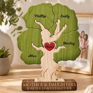 May include: A wooden family tree ornament with green leaves and a natural wood trunk. The tree features the names Phillip, Emily, Harley, and Alex, with "Mama" in a red heart. The base reads "MOTHER & DAUGHTERS FOREVER LINKED TOGETHER."