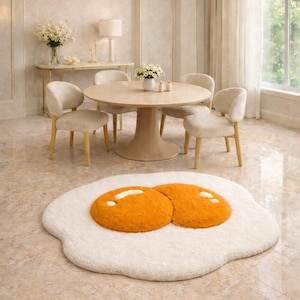 May include: A novelty rug in the shape of a fried egg, featuring a white base and two orange yolk sections. The rug is placed on a tiled floor in a dining room, with a round table and chairs in the background.