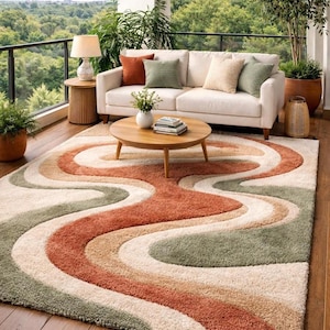 May include: A patterned rug with a retro design in shades of orange, green, beige, and cream. The rug is placed on a wooden floor in an outdoor setting, with a white sofa and a round coffee table. The rug's design is reminiscent of the 1970s.