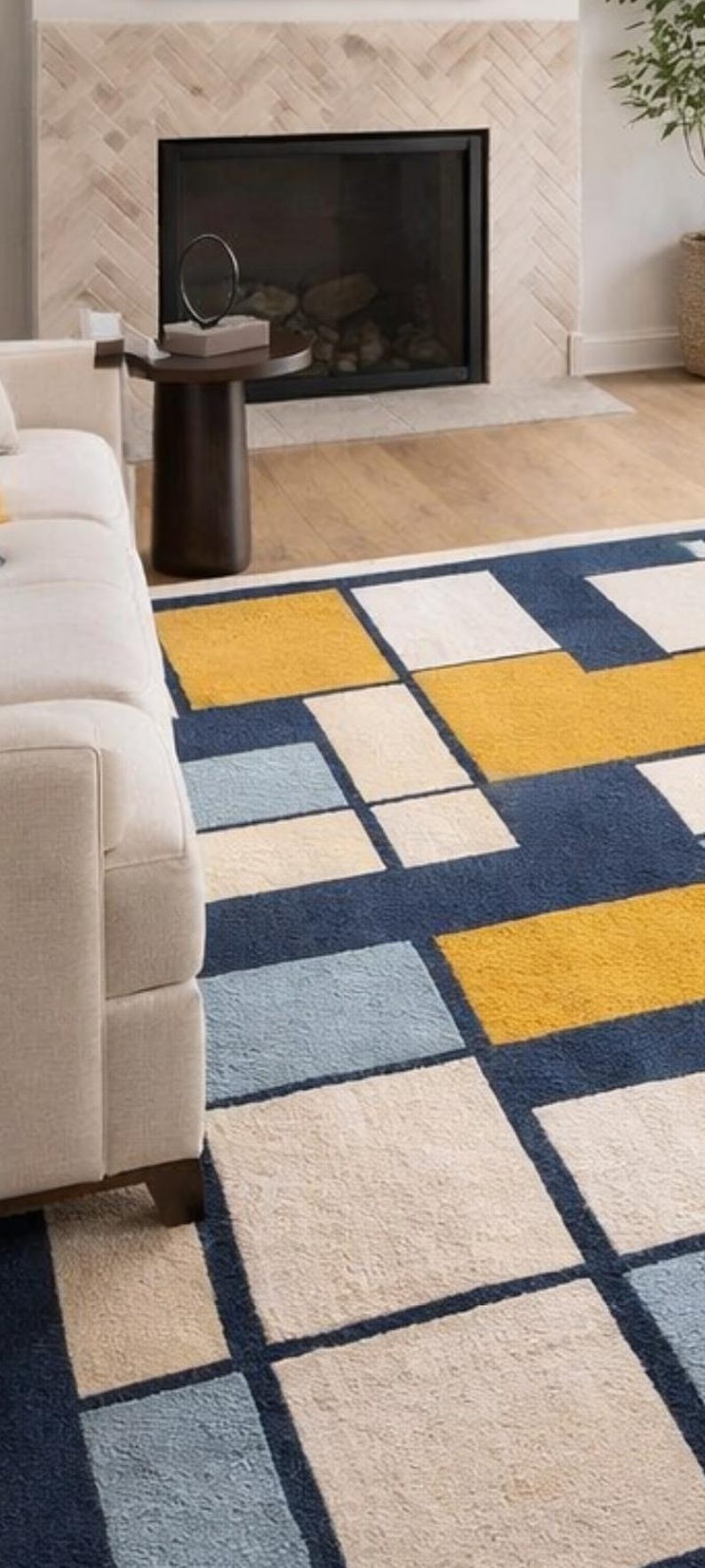 May include: A geometric patterned rug with a modern design. The rug features large rectangular blocks in navy blue, yellow, light blue, and cream colors. The rug is placed in a living room setting, with a white sofa visible in the frame.