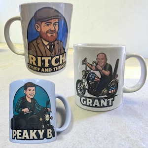 May include: Three white ceramic mugs with cartoon illustrations. One mug features a man in a cap with the text "RITCH STUFF AND THINGS." Another mug shows a man on a motorcycle with the text "GRANT." The third mug displays a man on a motorcycle with the text "PEAKY B."