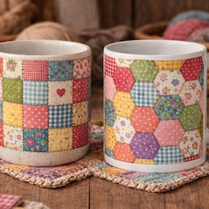 Peut inclure: Deux mugs en céramique blanche avec des motifs de patchwork. L'un présente des carrés avec un cœur, l'autre des hexagones. Les deux sont posés sur des dessous de verre assortis, pour une ambiance artisanale.