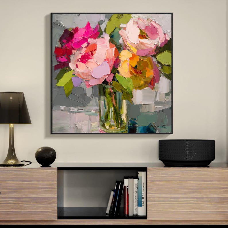 May include: A framed floral painting featuring a bouquet of colorful flowers in a clear glass vase. The flowers are painted with thick brushstrokes in shades of pink, red, and yellow, with green leaves. The painting has a modern, abstract style.